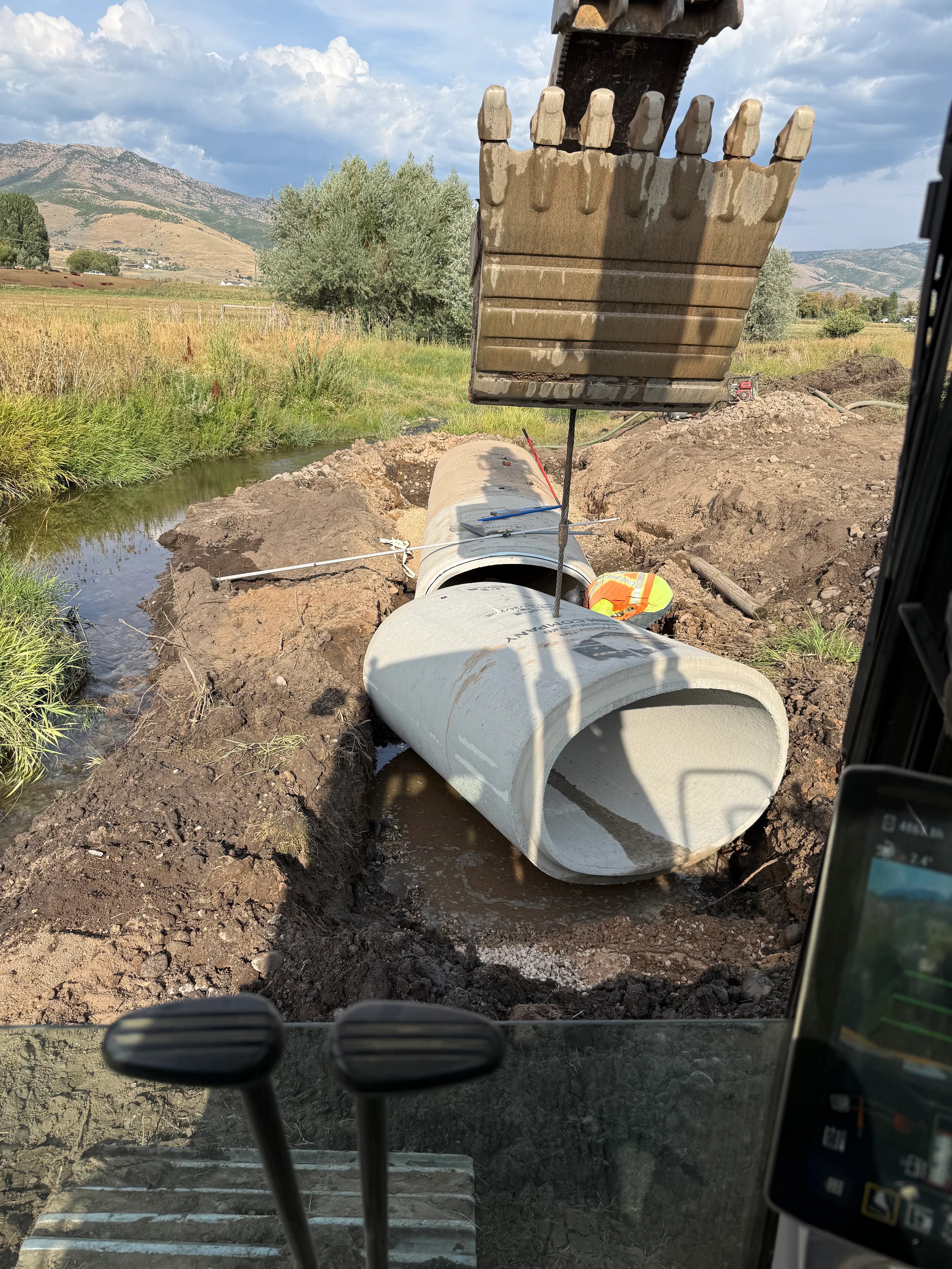 AccuRite Excavation installing a 48-inch elliptical concrete culvert pipe with mastic joints for low-clearance road drainage in Northern Utah