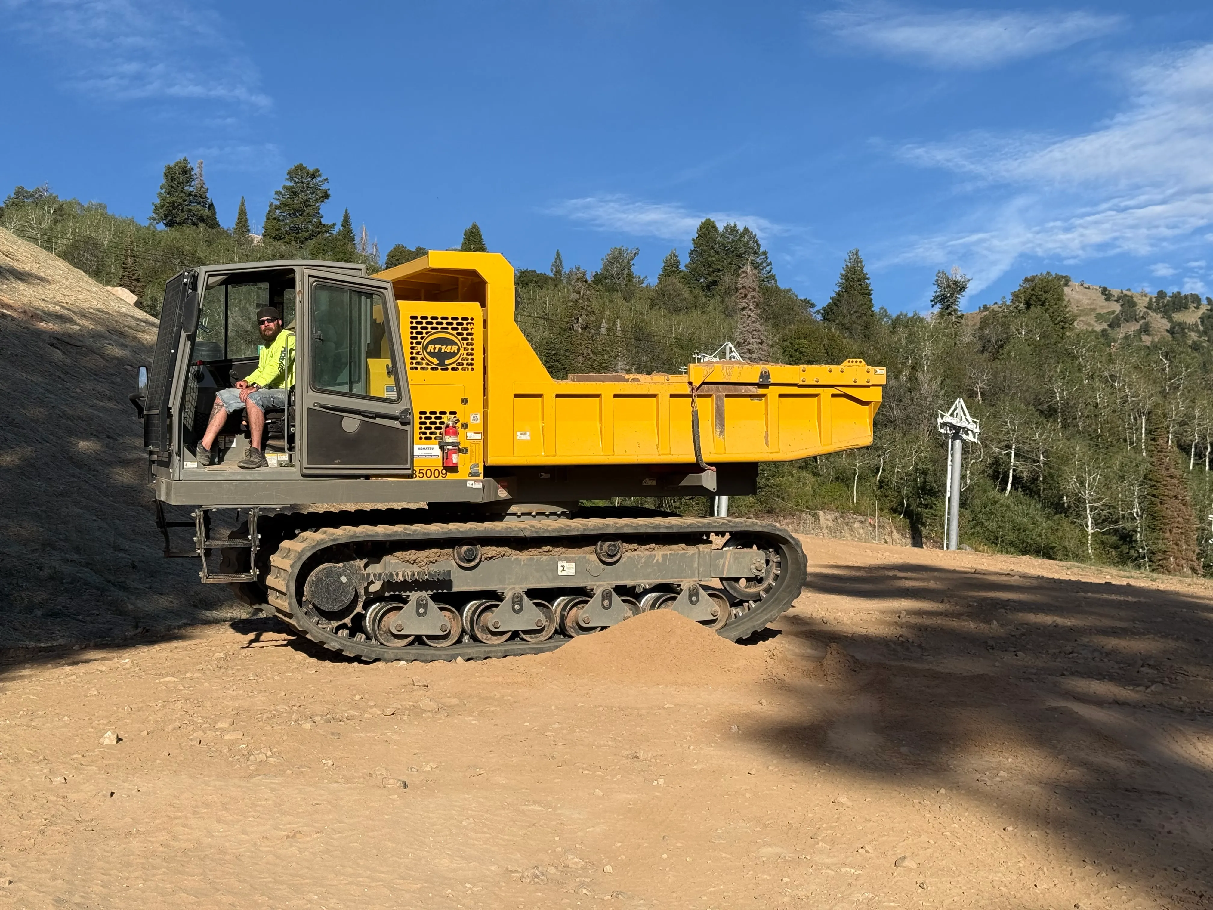 Specialized 360-degree rotating tracked dump truck hauling material across steep and soft ground on a Utah excavation site
