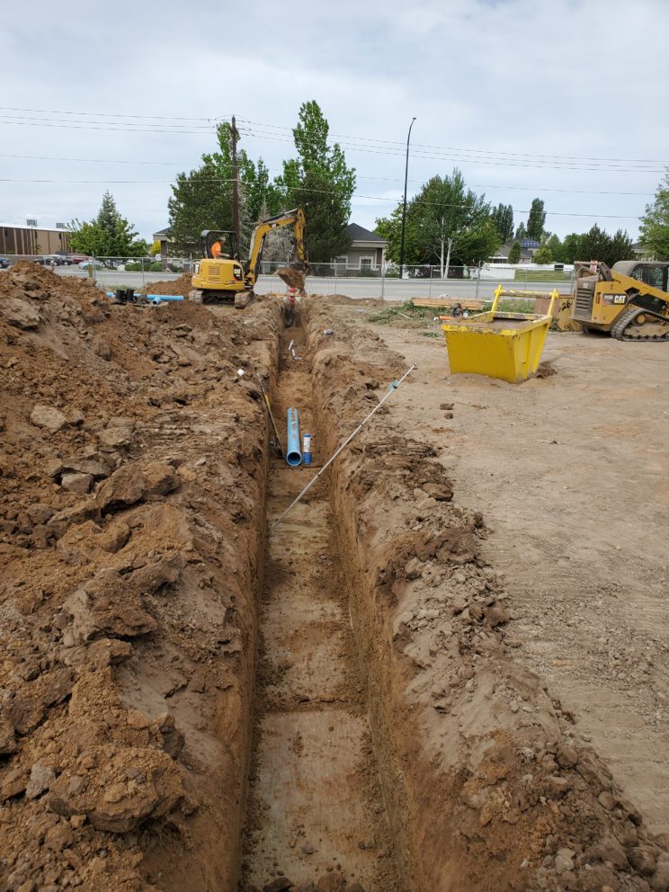 AccuRite Excavation's proficient team installing a main water line in Syracuse, Davis County, featuring multiple connections, culinary water mains, and fire hydrants, adhering to stringent bacteria and pressure testing standards.