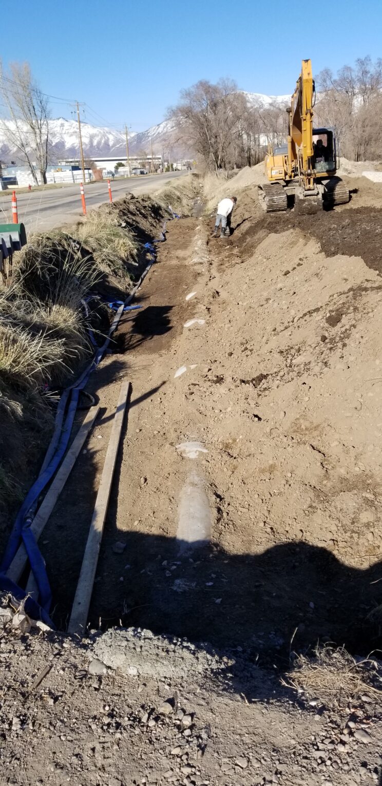 AccuRite Excavation team skillfully installing RCP storm drain pipe on a public right-of-way, utilizing precision laser technology for accurate joint alignment, with a temporary water line bypass in place.
